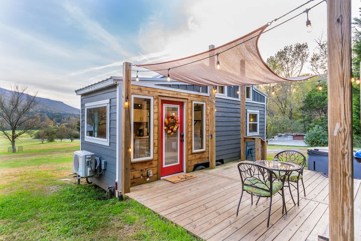The blue tiny home and its deck under a shade sail