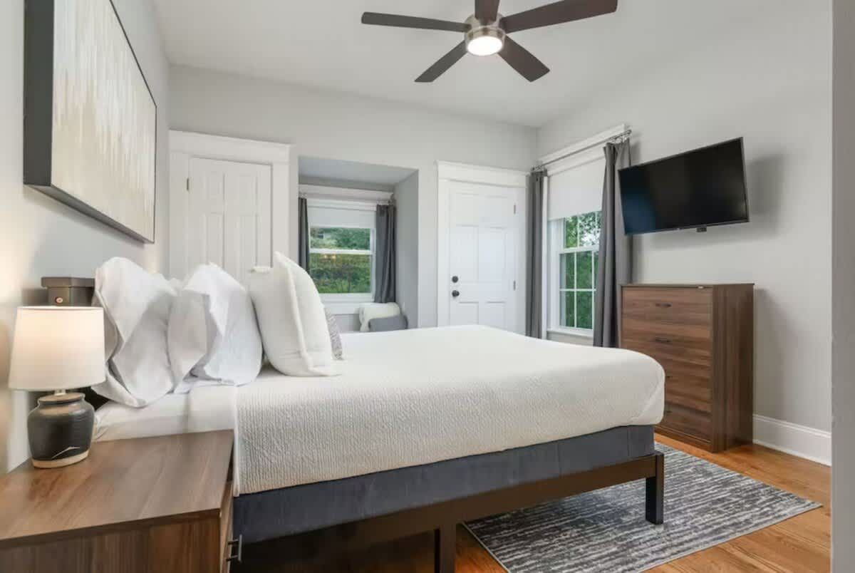 Bedroom with white bedding and a ceiling fan