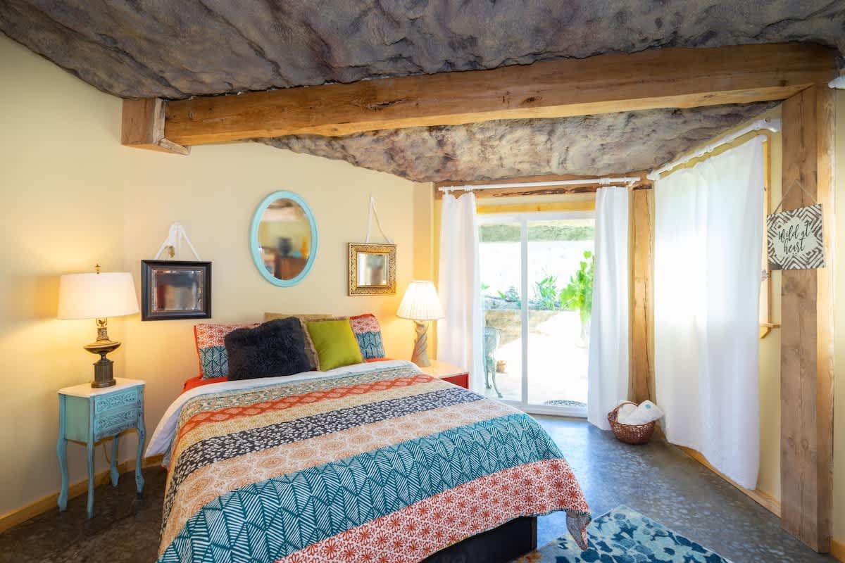 Bedroom with a colorful quilt and glass doors to the garden