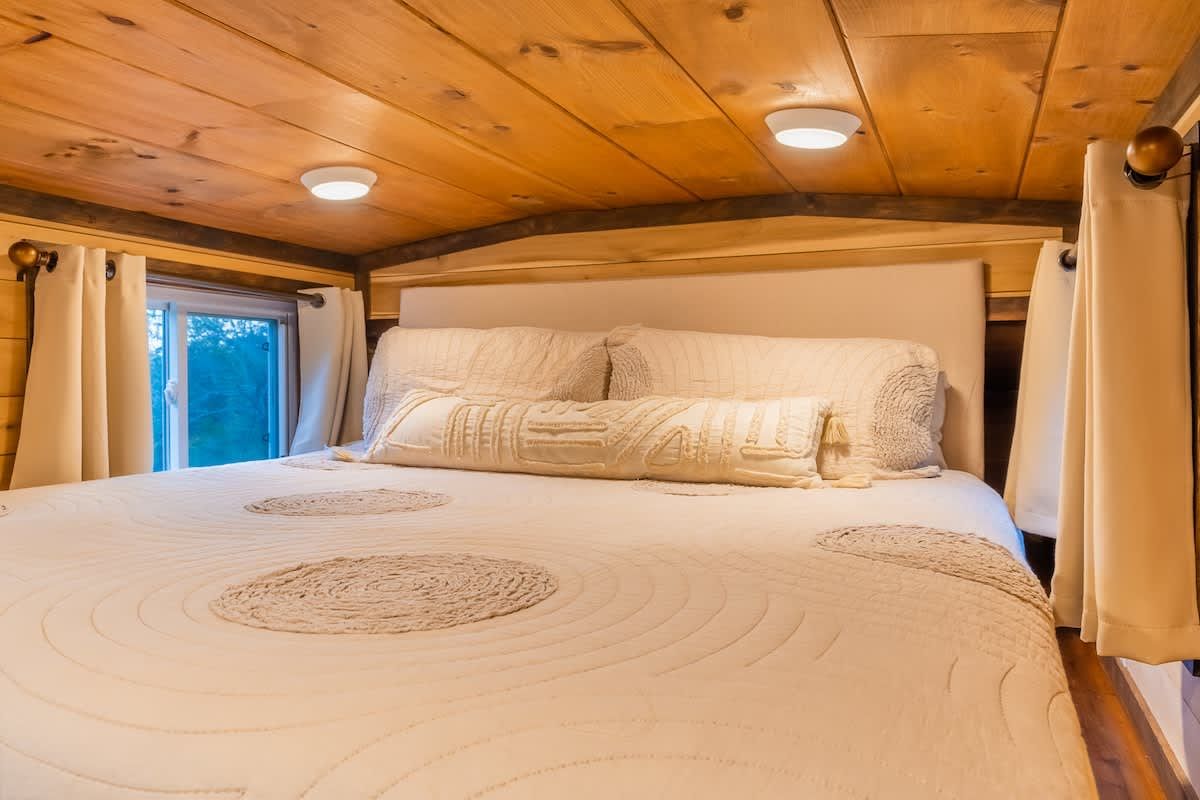 King bed in the loft under a wood ceiling