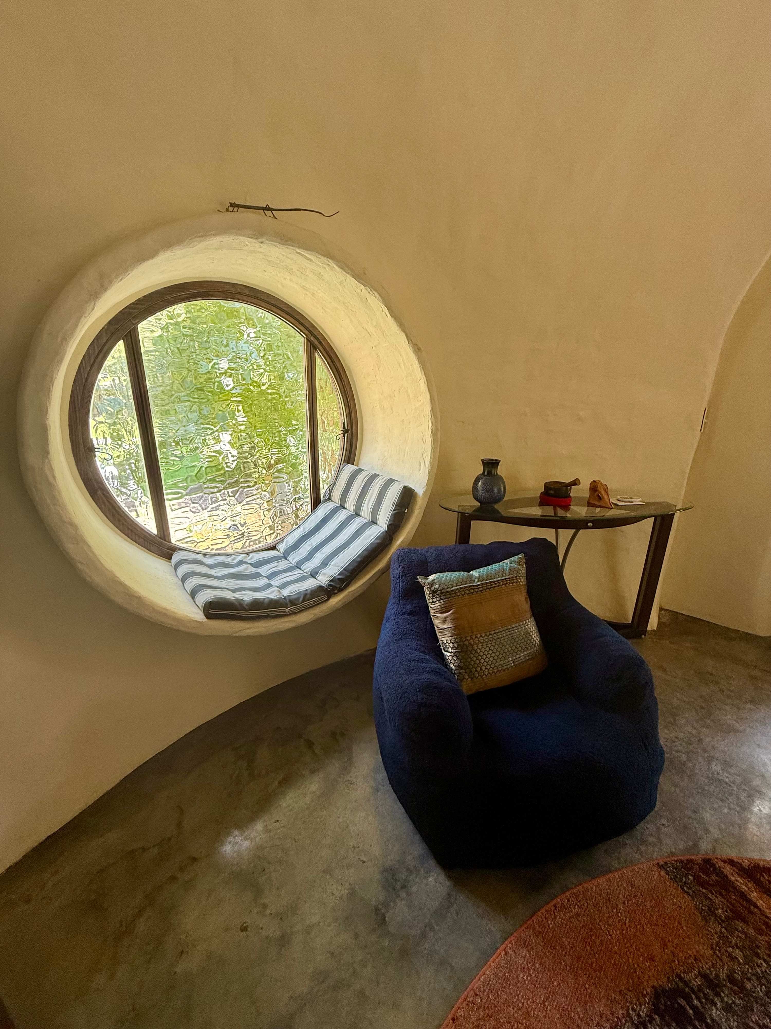 Round window seat with cushions looking into the woods