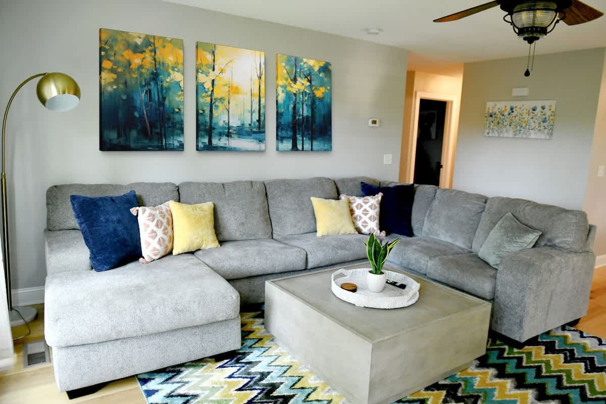 Gray sectional under a set of forest paintings