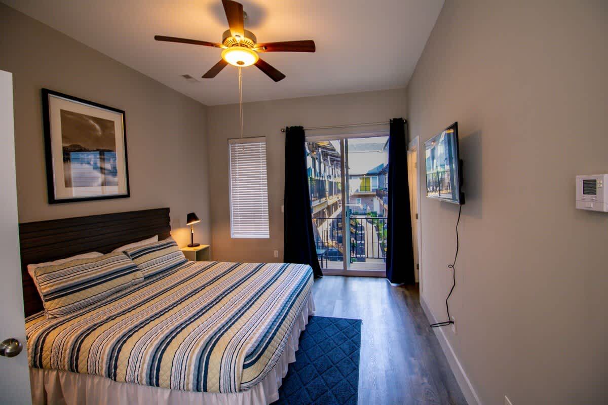Bedroom with a ceiling fan and doors to a balcony
