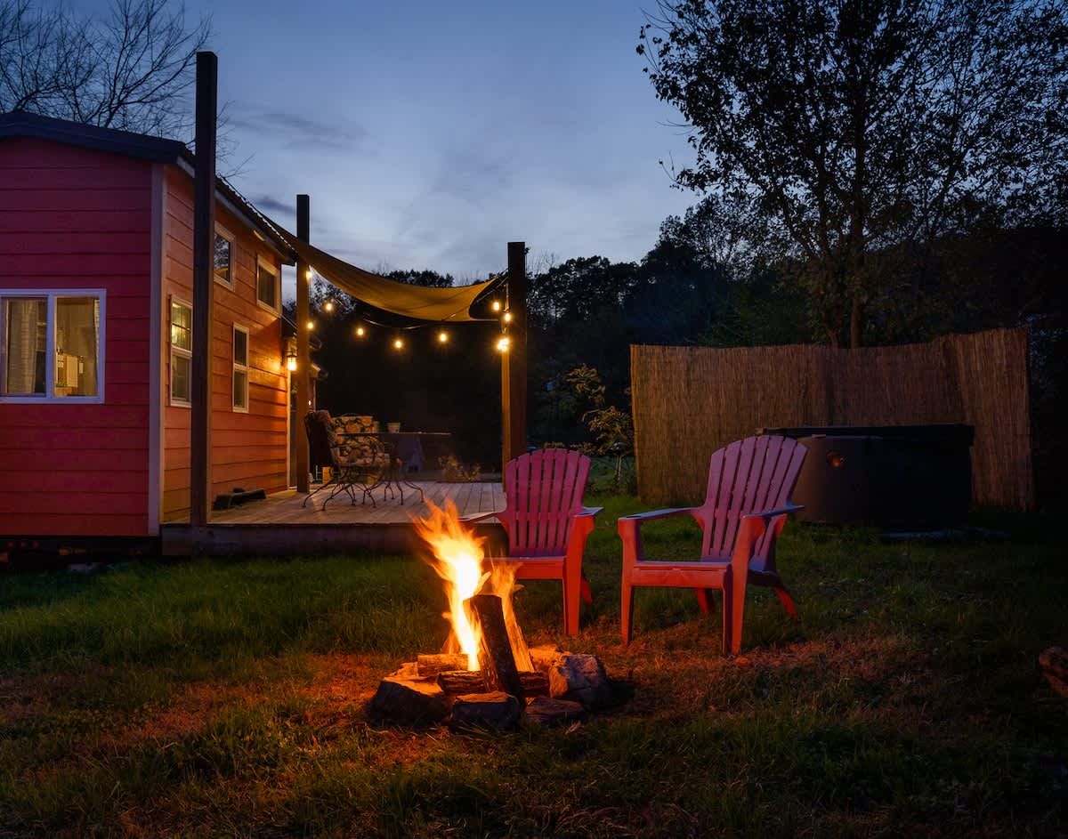 Fire pit glowing in the evening beside the tiny home