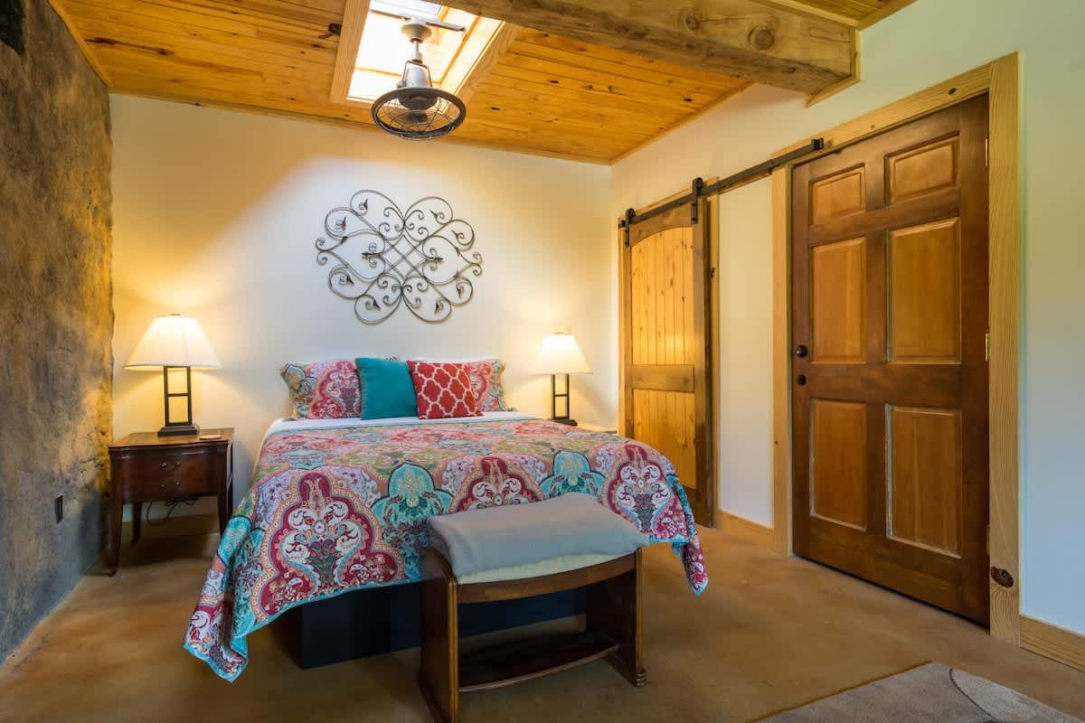 Queen bedroom with a skylight, barn doors and a patterned quilt
