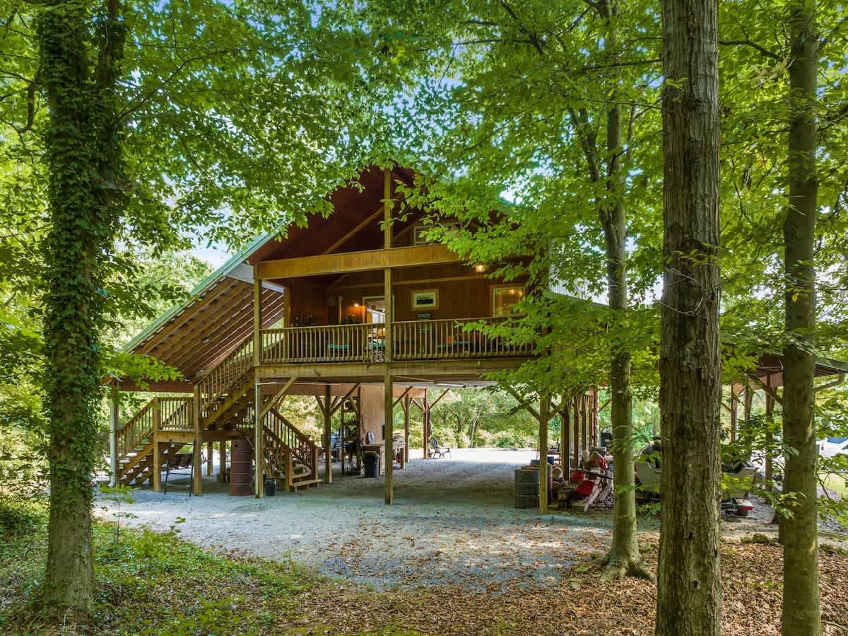 The wood cabin raised above a barn in the trees