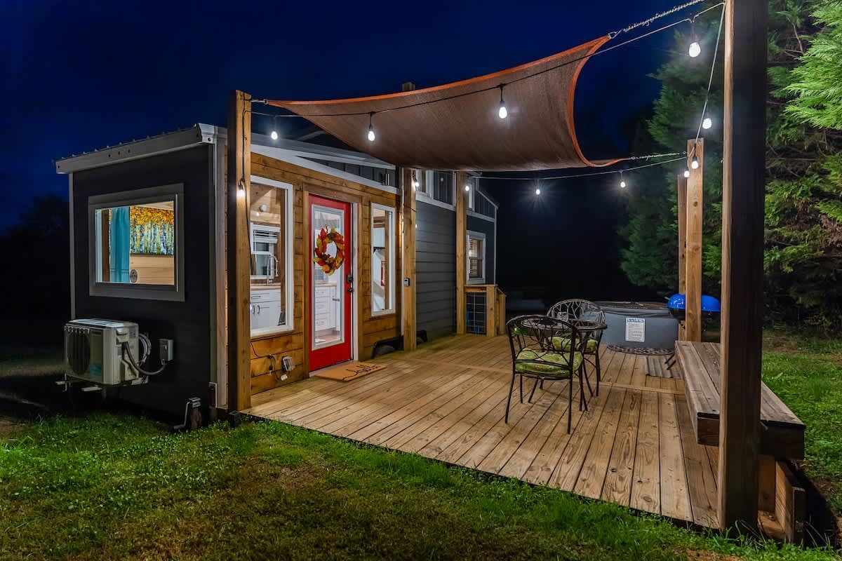 The tiny home and deck lit up at night