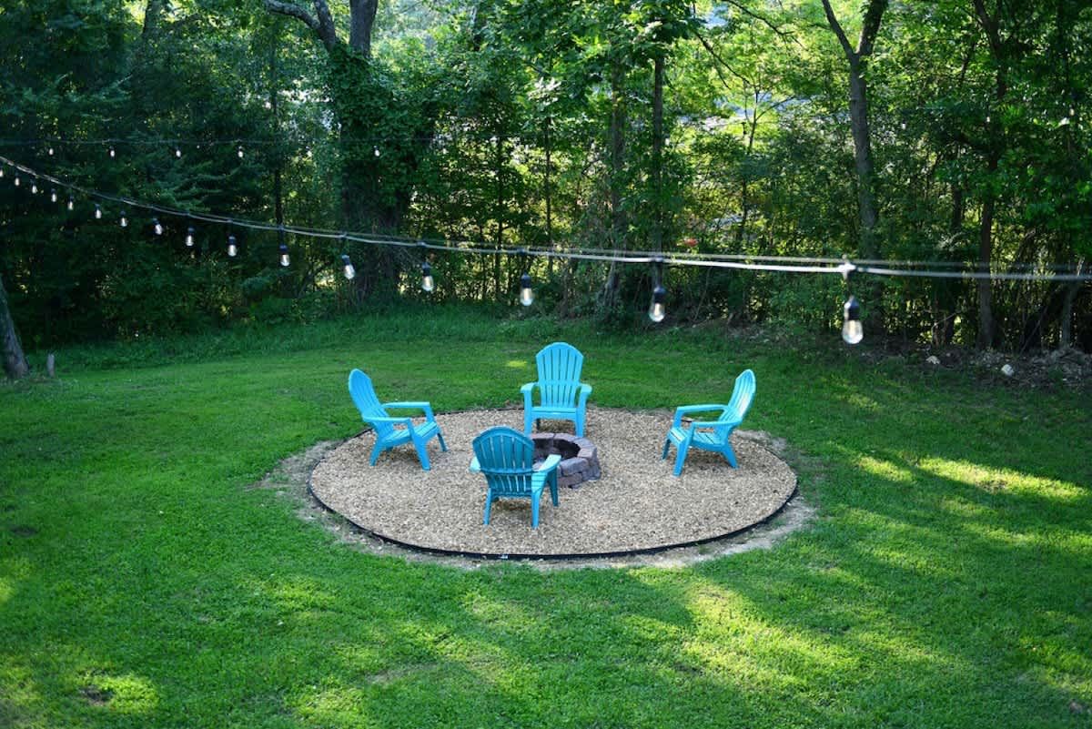 Fire pit ringed by blue chairs under string lights